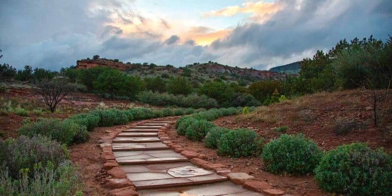 120steps-blog Scenic stone walking path winding through Sedona’s natural red rock terrain at sunrise, offering a peaceful environment for reflection and grounding.