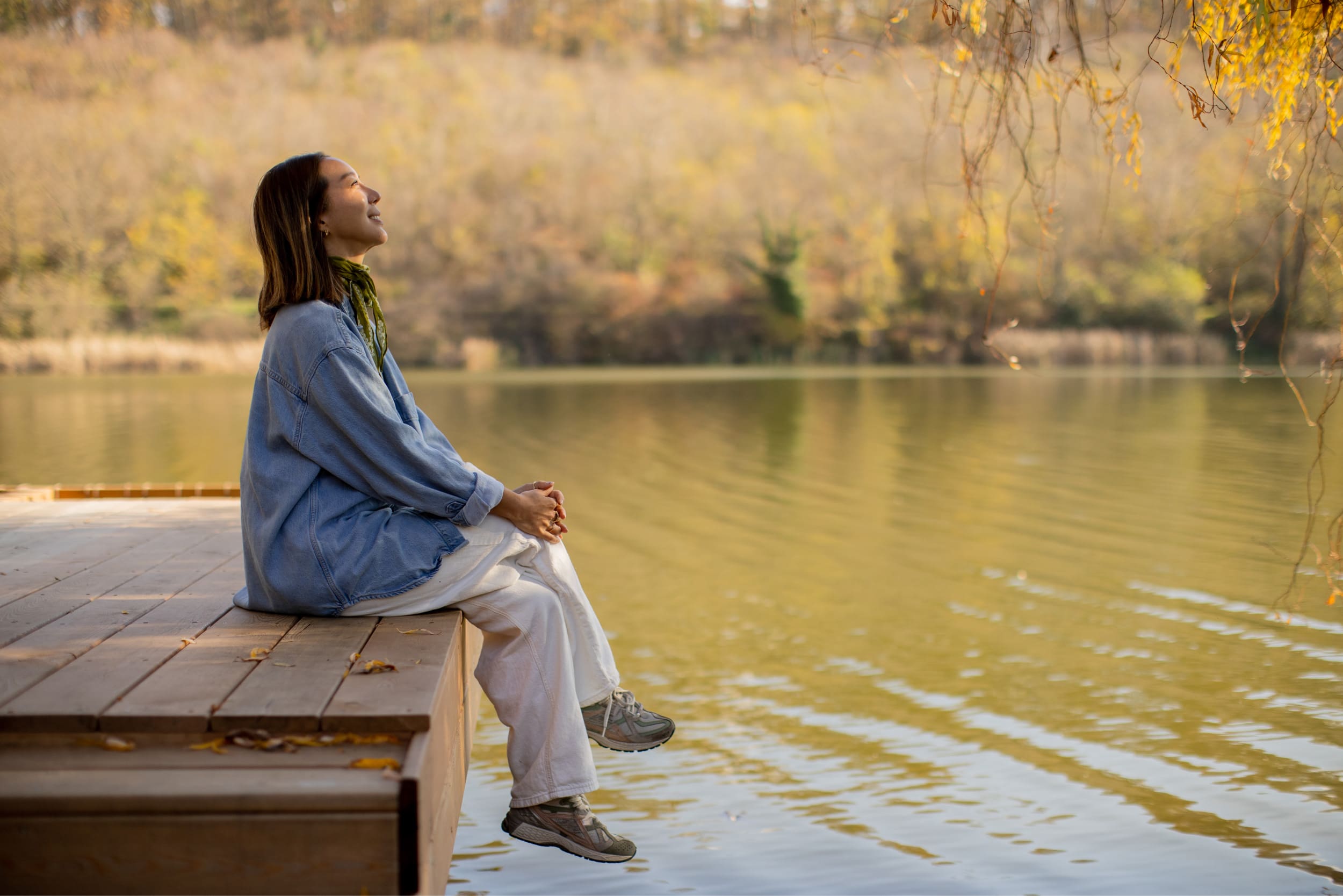 Gina-Program-FAQ-01-2 Woman sitting by a lakeside enjoying a peaceful moment during an in-person retreat